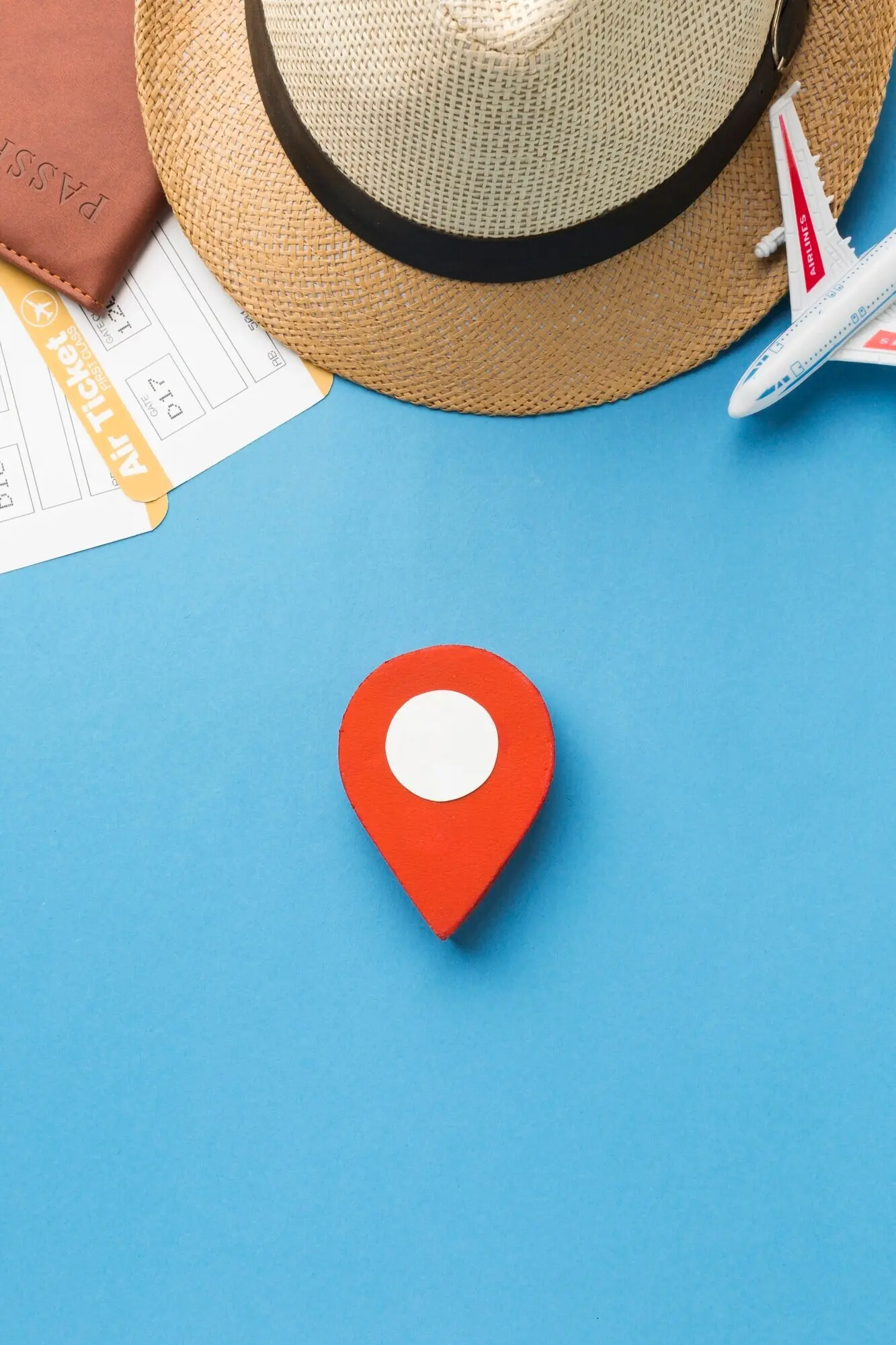 Overhead view of a hat and travel essentials with a pinpoint.